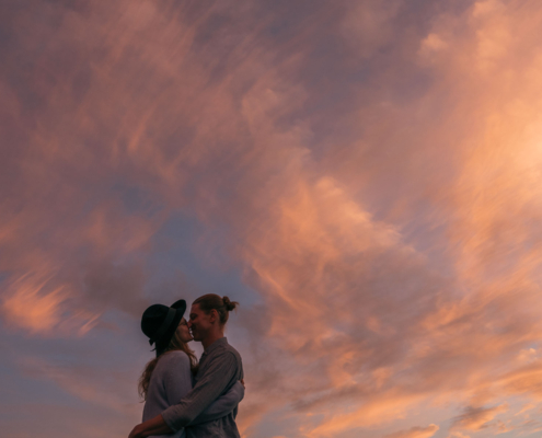 Küssendes Paar vor orange-leuchtendem Abendhimmel