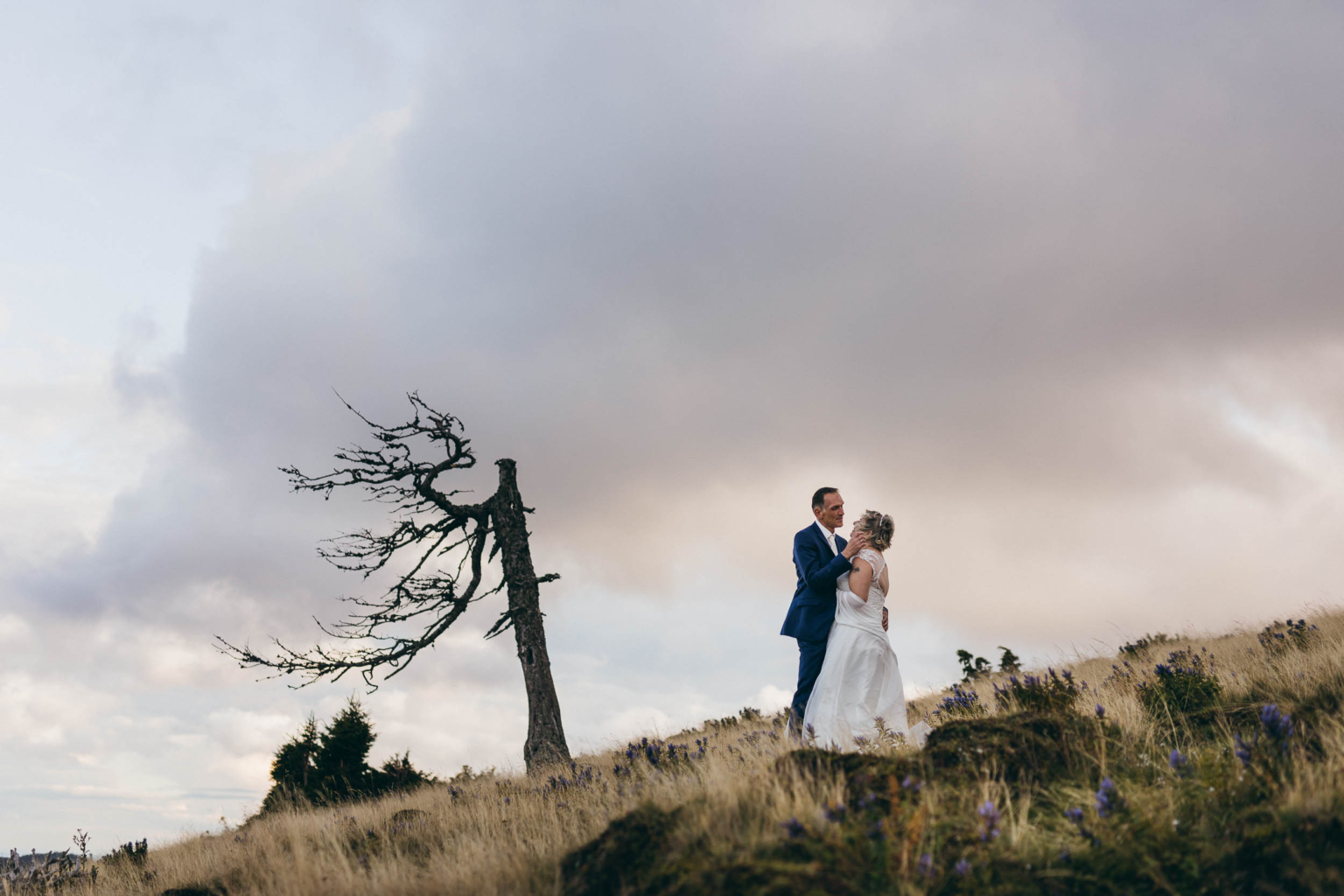 Traumhafte Portraits mit Braut und Bräutigam vor lila Wolken beim After-Wedding-Shooting auf der Teichalm, Sommeralm