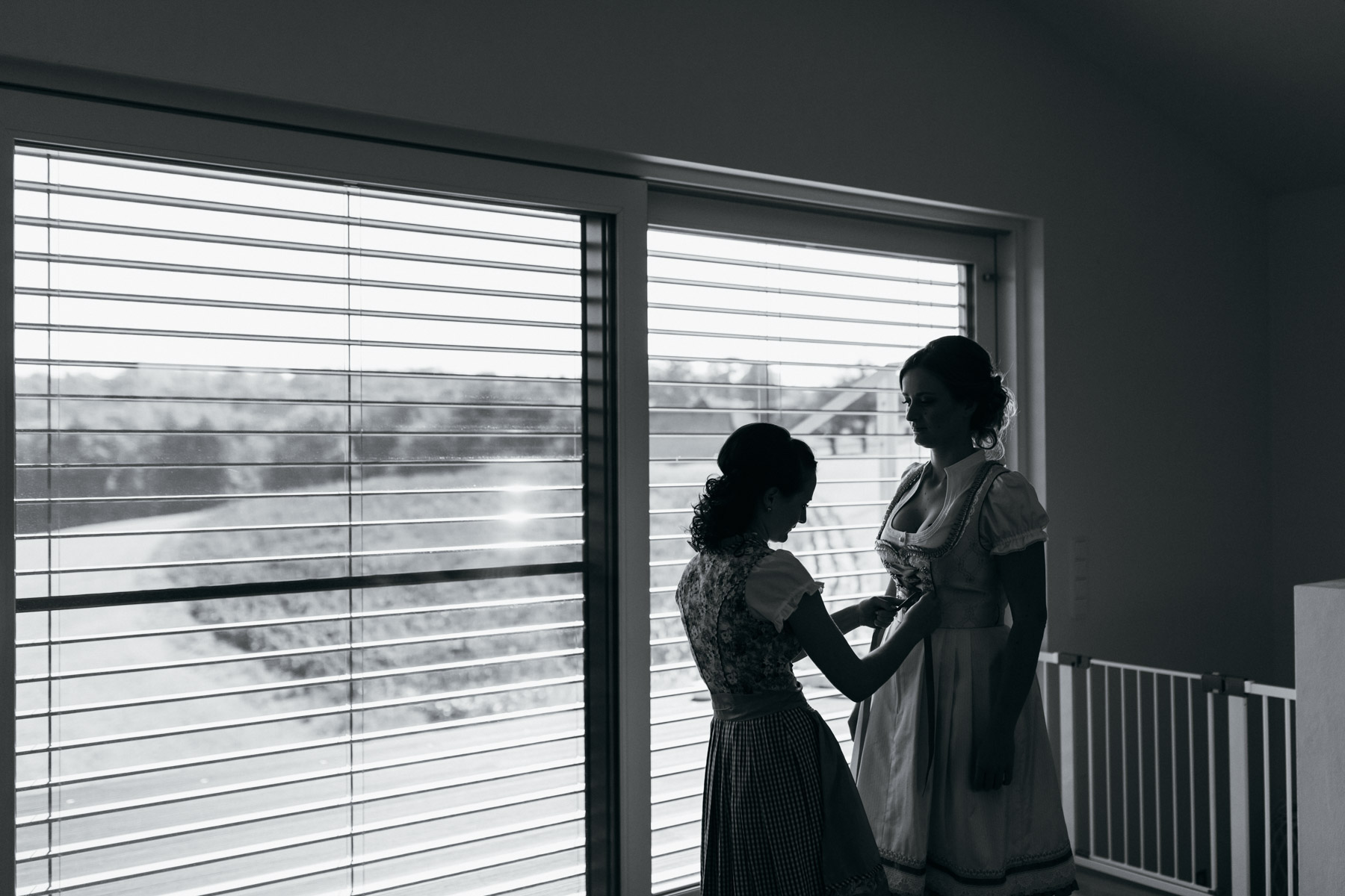 Braut und Trauzeugin beim Getting-ready vor dem Fenster als Silhouette, Schwarz-Weiß