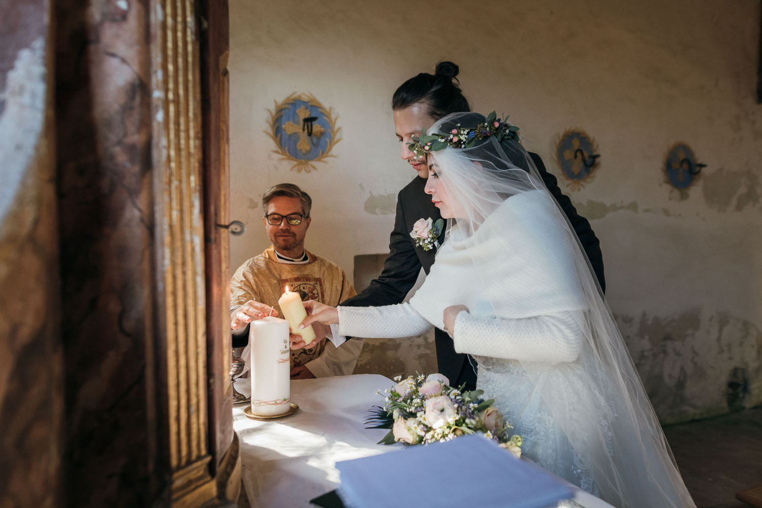 Atemberaubendes Hochzeitsfoto vom Anzünden der Kerze in einer kleinen Kapelle nördlich von Graz, Steiermark