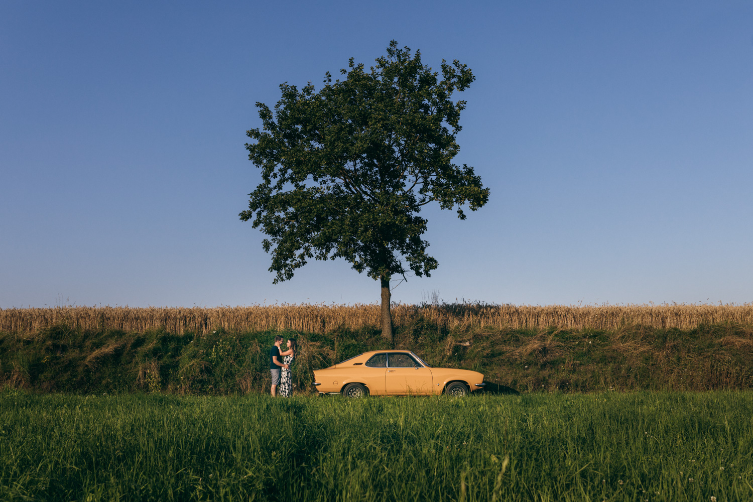 Paarportraitshooting mit gelbem Opel Manta im Sommer