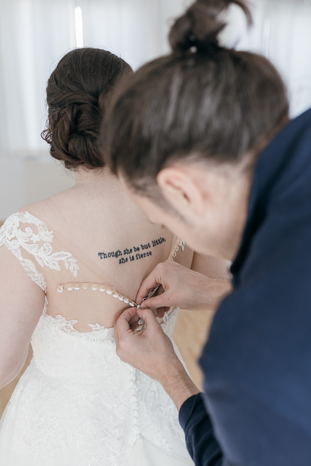 Bräutigam hilft Braut beim Ankleiden bei der intimen Hochzeit Graz