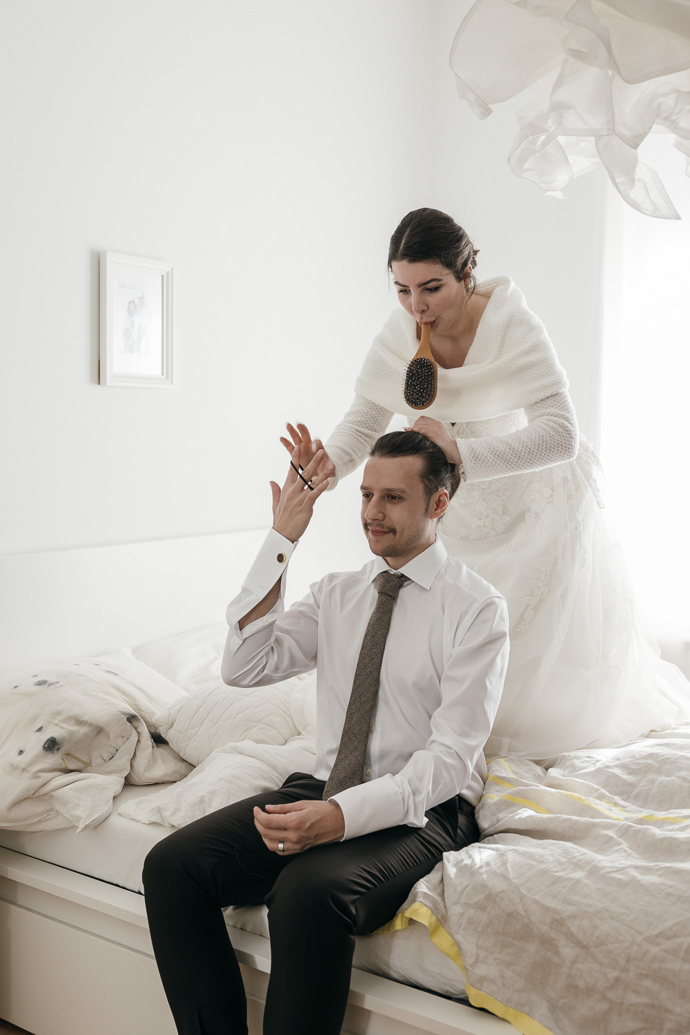 Braut hilft Bräutigam beim Styling im Schlafzimmer