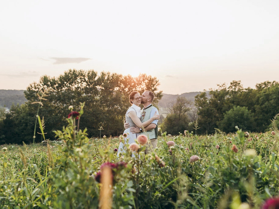 romantische-hochzeitsfotos-hochzeitsfotograf-steiermark-vom-huegel-a-wild-emotion-mobil-2026 Du willst romantische Brautpaarportraits? Dann versuche es mit Bridalportraits im Blumenfeld bei Sonnenuntergang!